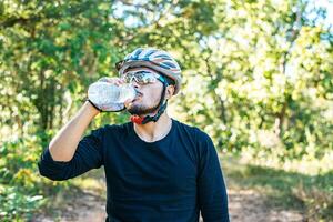 Cyclists stand on the top of the mountain and drink a bottle of water. photo