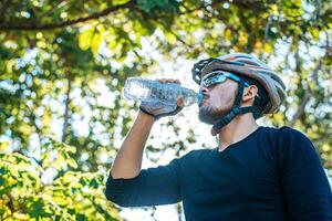 los ciclistas se paran en la cima de la montaña y beben una botella de agua. foto