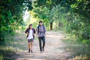 Young couple walking with backpacks in forest. Adventure hikes. photo