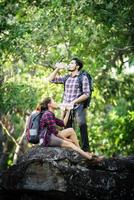 Young couple walking with backpacks in forest. Adventure hikes.