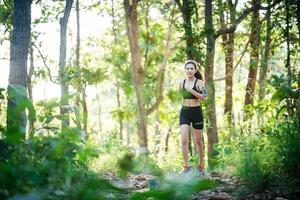 Young woman jogging on rural road in green forest nature.