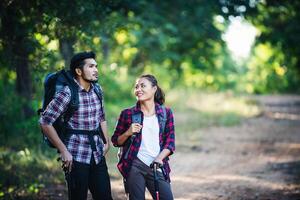 Young couple walking with backpacks in forest. Adventure hikes. photo