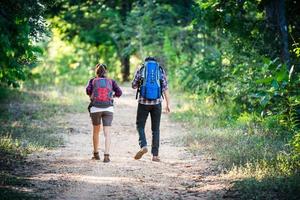Young couple walking with backpacks in forest. Adventure hikes. photo
