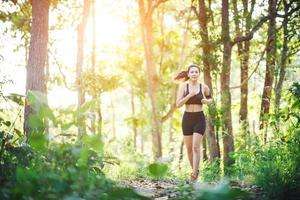 mujer joven para correr en un camino rural en la naturaleza del bosque verde. foto