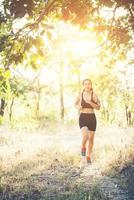 Young woman jogging on rural road in forest nature. photo