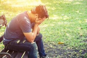 headache man sitting on bench in the park. photo