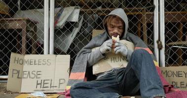 hombre sin hogar sentado frente a una puerta