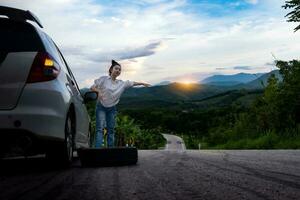 Young beautiful lady standing near car for calling for help photo