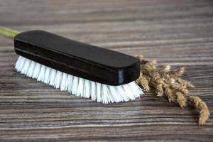 Clothes brush on a wooden background. Black wooden shoe brush photo