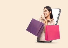 Young woman holding shopping bags via smartphone photo