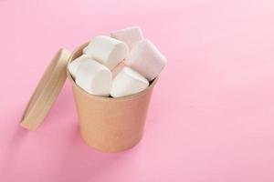 Marshmallow in bucket on pastel pink background photo