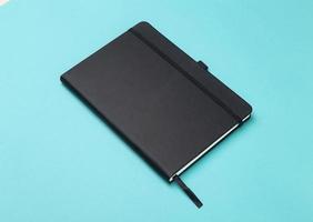 Black notebook isolated on blue background photo