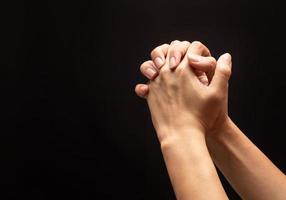 Hands out in prayer on black background photo