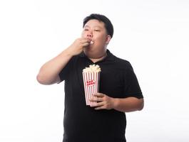 Hombre asiático comiendo palomitas de maíz sobre fondo blanco. foto