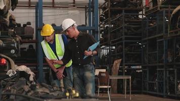 deux ouvriers masculins vérifiant les pièces du moteur dans un entrepôt. video