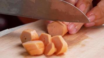 close-up da mão de uma mulher segurando uma faca, cortando salsichas. video
