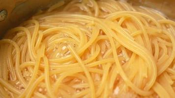 espaguete cru está sendo cozido em água fervente em uma panela de cozinha. video