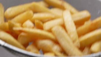 Nahaufnahme der Hand mit Salz auf Pommes frites bestreut. video