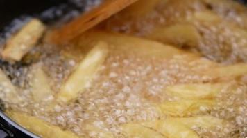 närbild av stekning pommes frites i fritösen i varm olja. video