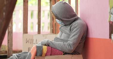 Hombre sin hogar en una mascarilla sosteniendo un cartel de ayuda por favor video