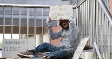 hombre sin hogar sentado y sosteniendo carteles video