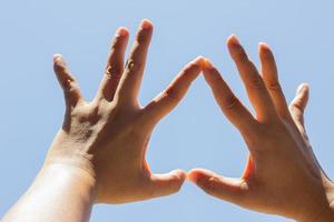 mano de niña en forma de corazón al revés amor cielo azul foto