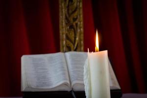 Biblia con velas en el fondo. escena con poca luz. foto