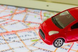 Foto horizontal del primer coche de juguete rojo en el mapa en la pantalla de la tableta