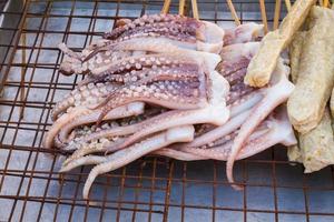 Calamares a la plancha con brocheta de bambú sobre colador plano. foto