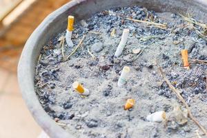Smoked Cigarettes Butts in a Public Ashtray, selective focus photo