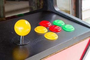yellow joystick of an old arcade video game with six colorful button photo