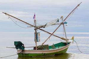 Barco de pesca con bandera tailandesa flotando en el mar foto