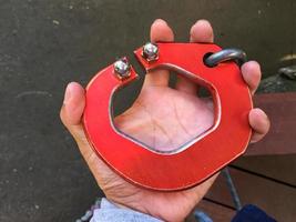 horizontal photo of big red carabiner on man's left hand.