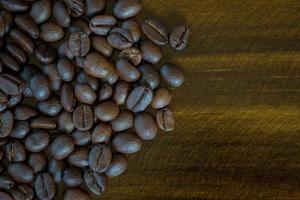 Granos de café de primer plano extrema sobre fondo de madera, tono oscuro. vista superior foto
