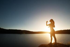 silhouette of sport woman hikes to the top of mountain sunset photo