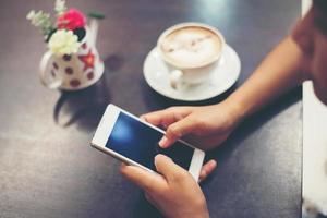 primer plano de la mujer manos mensajes de texto con su móvil en la cafetería. foto
