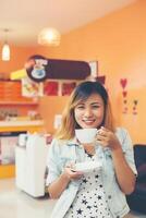 Young beautiful woman drinking hot cappuccino coffee at cafe. photo