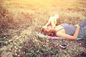 mujer escuchando música desde el teléfono inteligente en el campo de flores disfrutar. foto