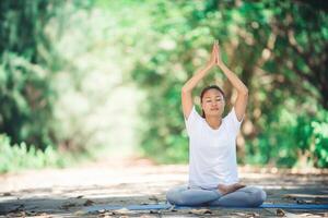 Young asian woman doing yoga in the morning at the park. Healthy photo