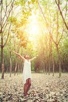 Young beautiful woman raised arms enjoying the fresh in green forest. photo