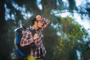 Hombre caminante cansado con una mochila grande durante la caminata en el bosque. foto