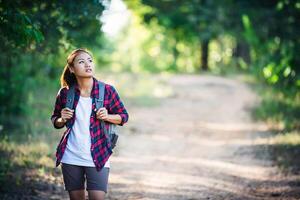 Young woman hiker with backpack walking and smiling on a country trail photo