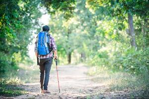 Young hipster man walking on the rural road during hikes on vacation. photo