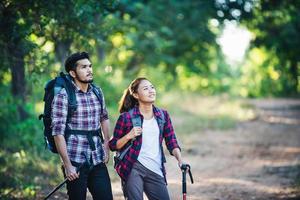 Young couple walking with backpacks in forest. Adventure hikes. photo
