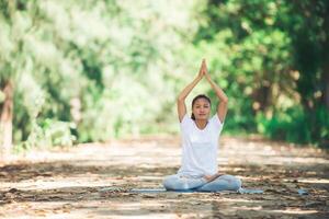 joven asiática haciendo yoga por la mañana en el parque. saludable foto