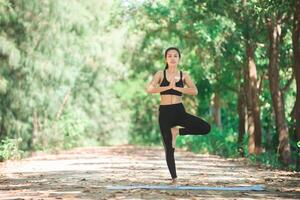 joven asiática haciendo yoga por la mañana en el parque. saludable foto