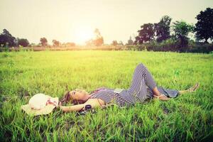 Young beautiful woman listening to music while lying down on grass. photo