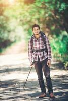 Hipster man hiker holding poles and looking away. photo