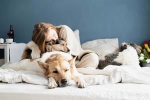 young woman sitting in the bed playing with her dogs, focus on dog photo