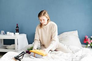 Mujer joven organizando ropa sentada en la cama en casa foto